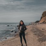 A woman standing on a peaceful Lithuanian beach by the Baltic Sea, showcasing a tranquil outdoor scenery.